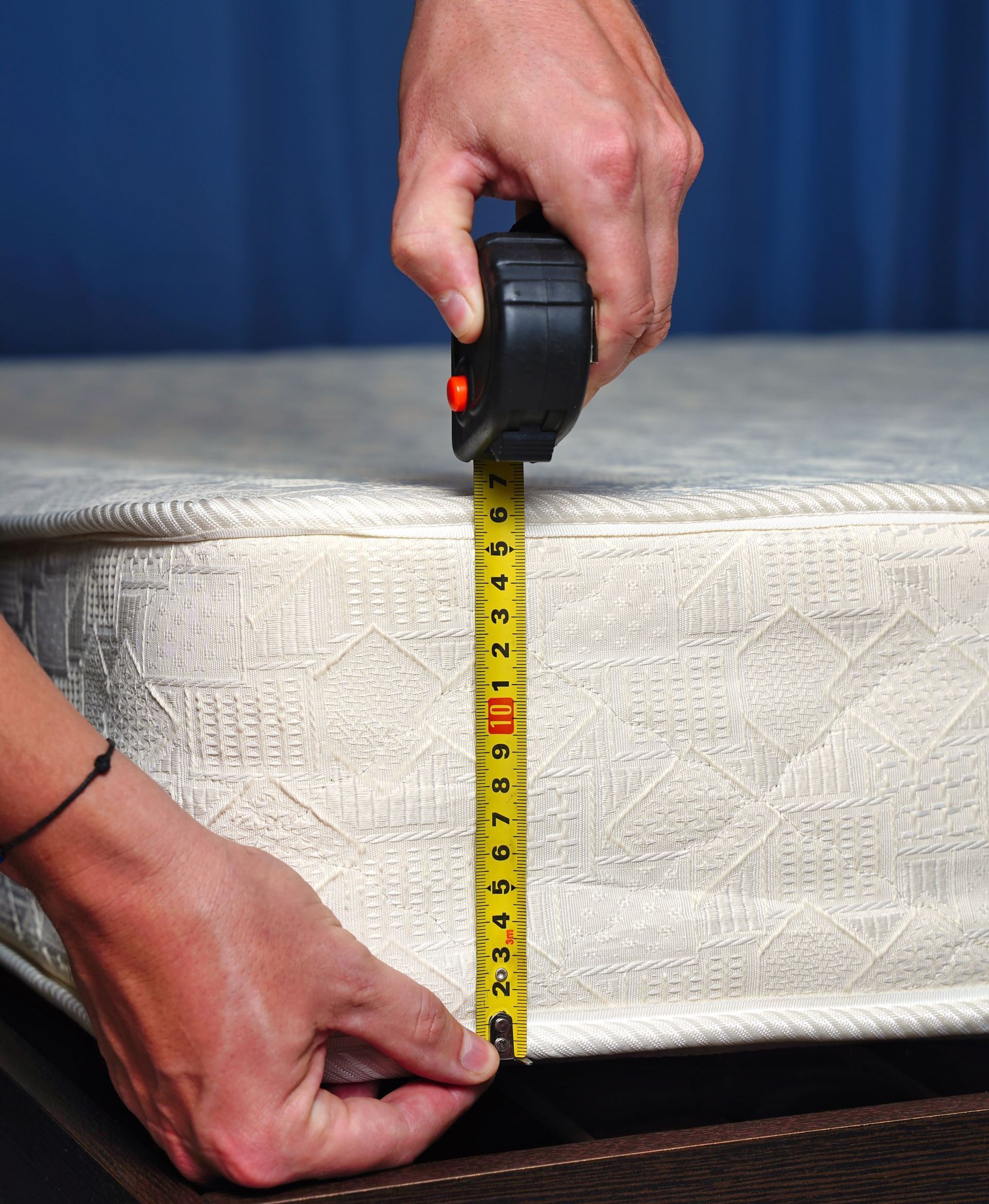 A man is measuring a couch with a tape measure.