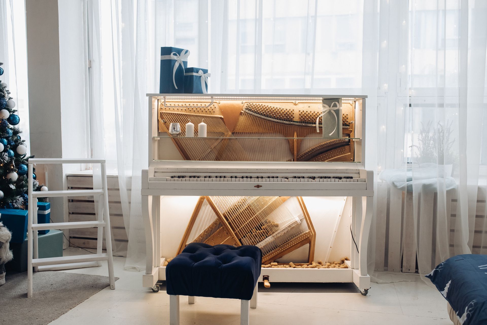 A white piano is sitting in a living room next to a christmas tree.