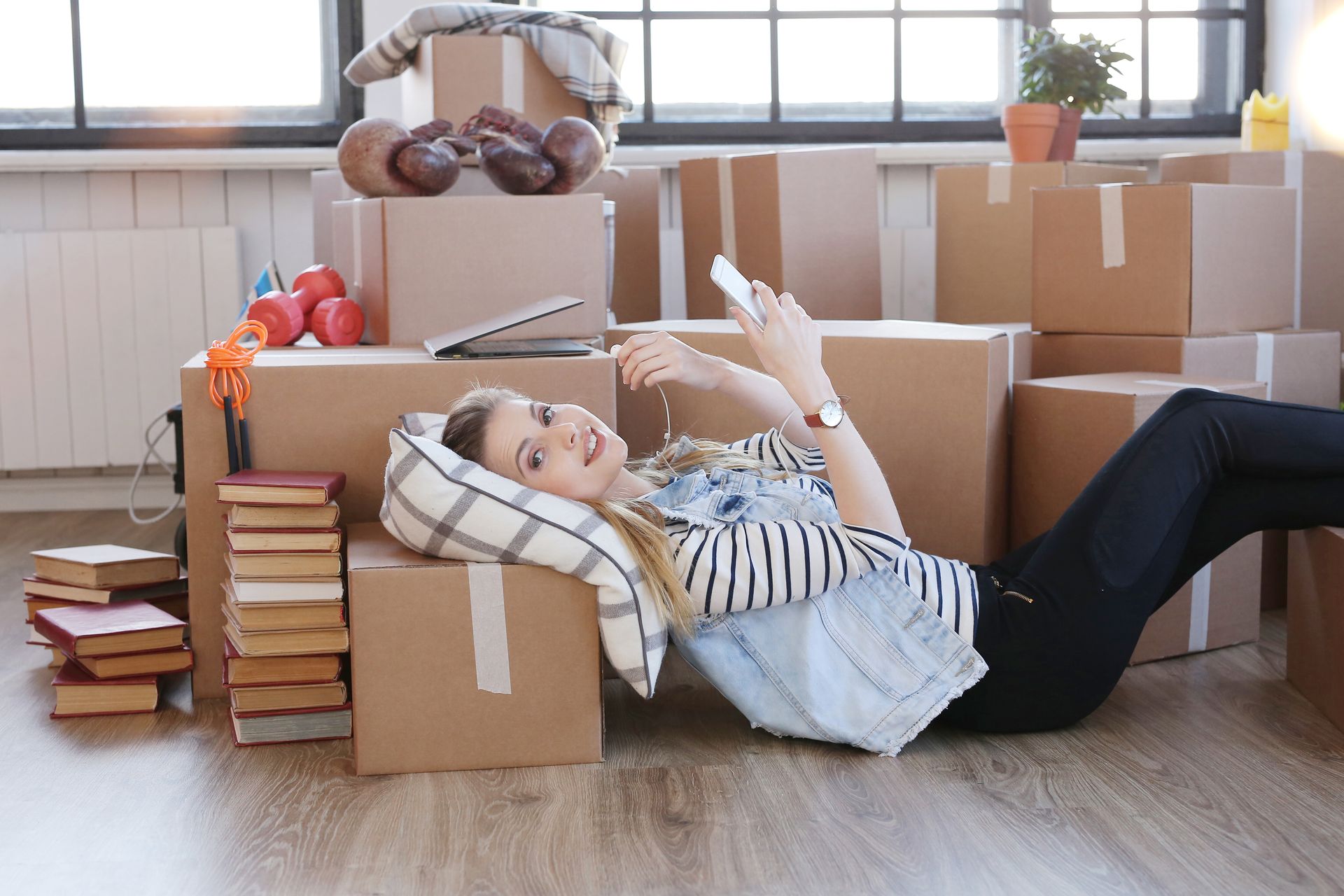 A woman is laying on the floor surrounded by cardboard boxes on moving day.