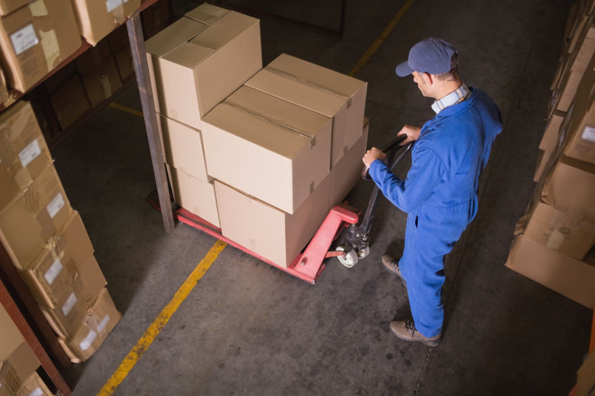 A man is pushing a pallet with boxes on it in a warehouse.