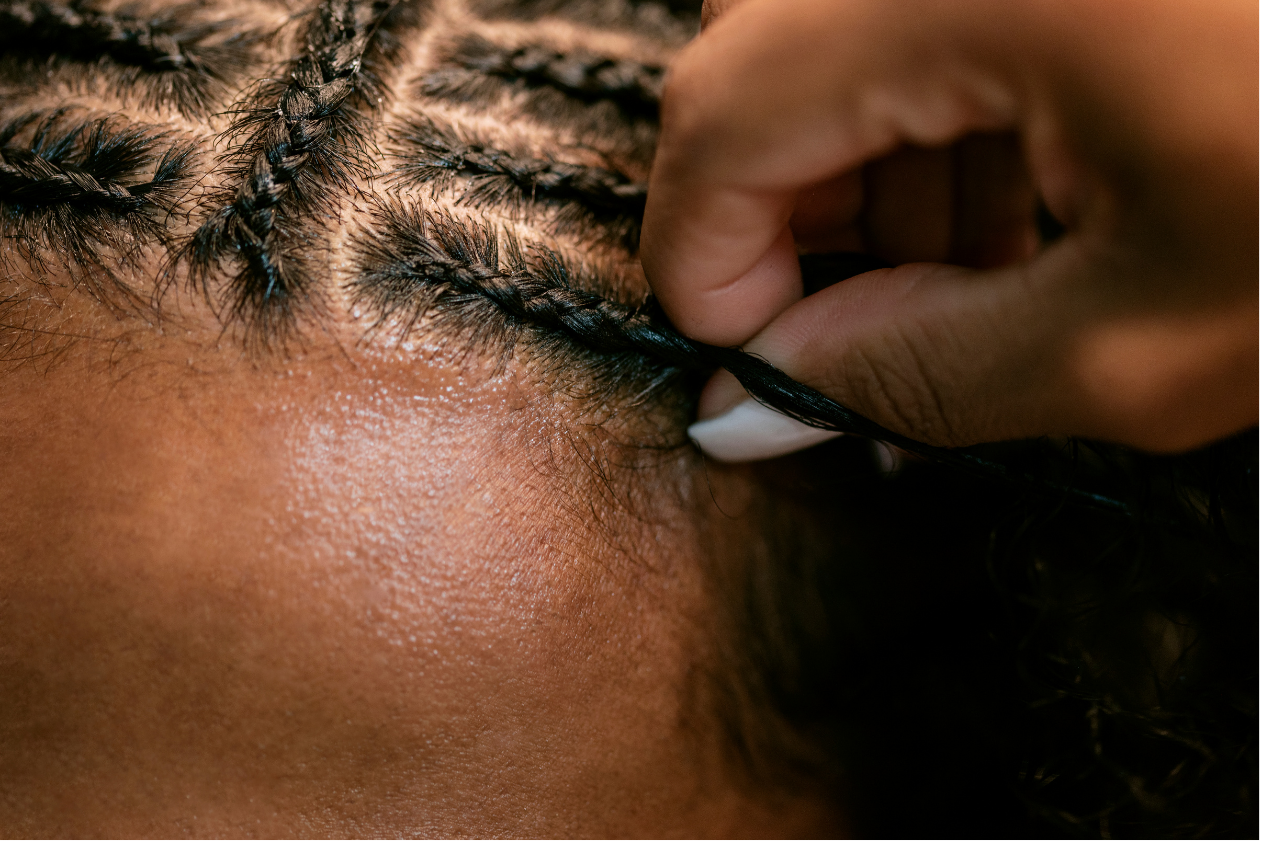 A close up of a person braiding a woman 's hair.
