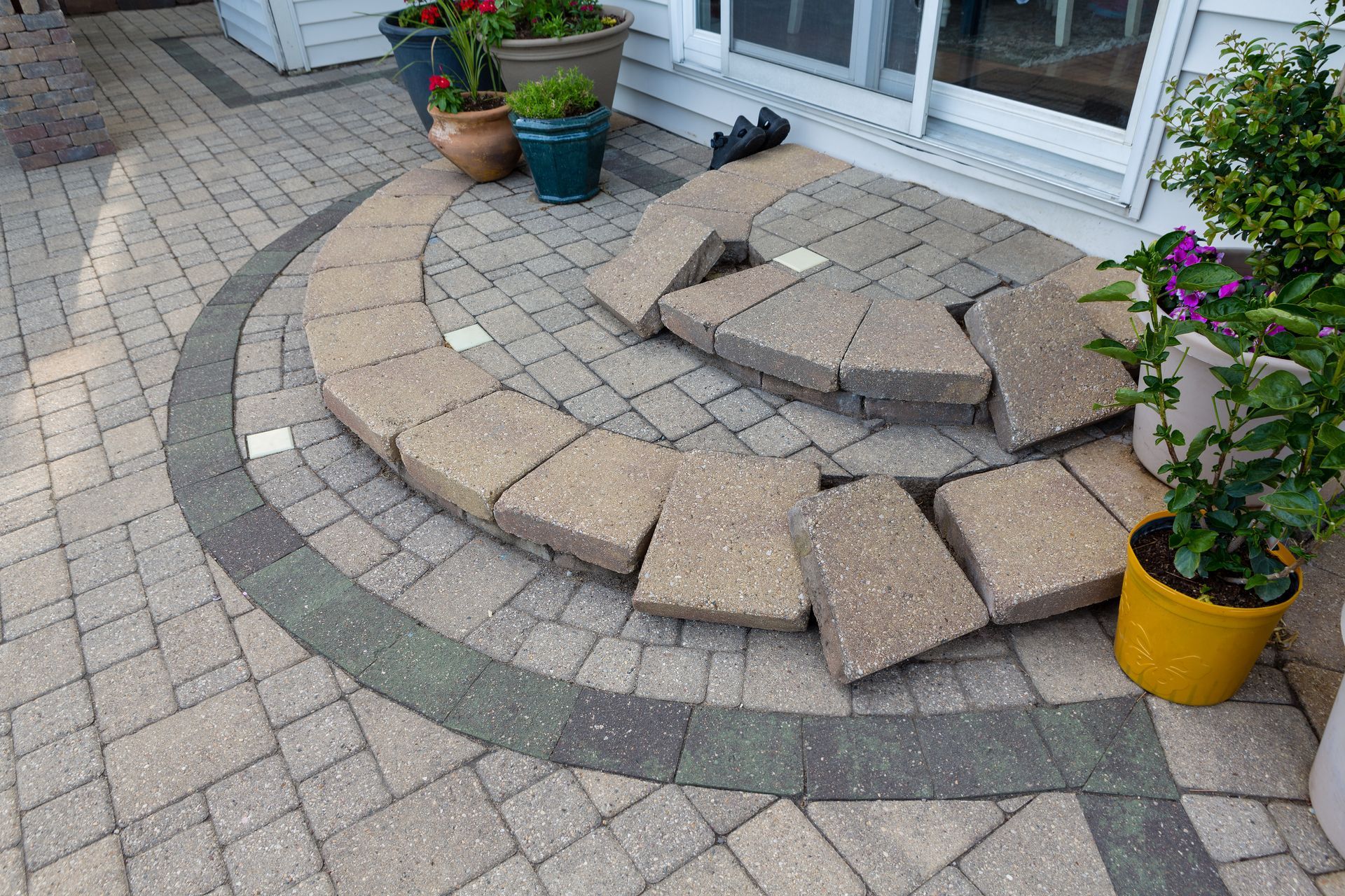 A semicircular patio step made of beige stone pavers, showing uneven placement and gaps in front of a sliding door. A semicircular patio step made of beige stone pavers, showing uneven placement and gaps in front of a sliding door.