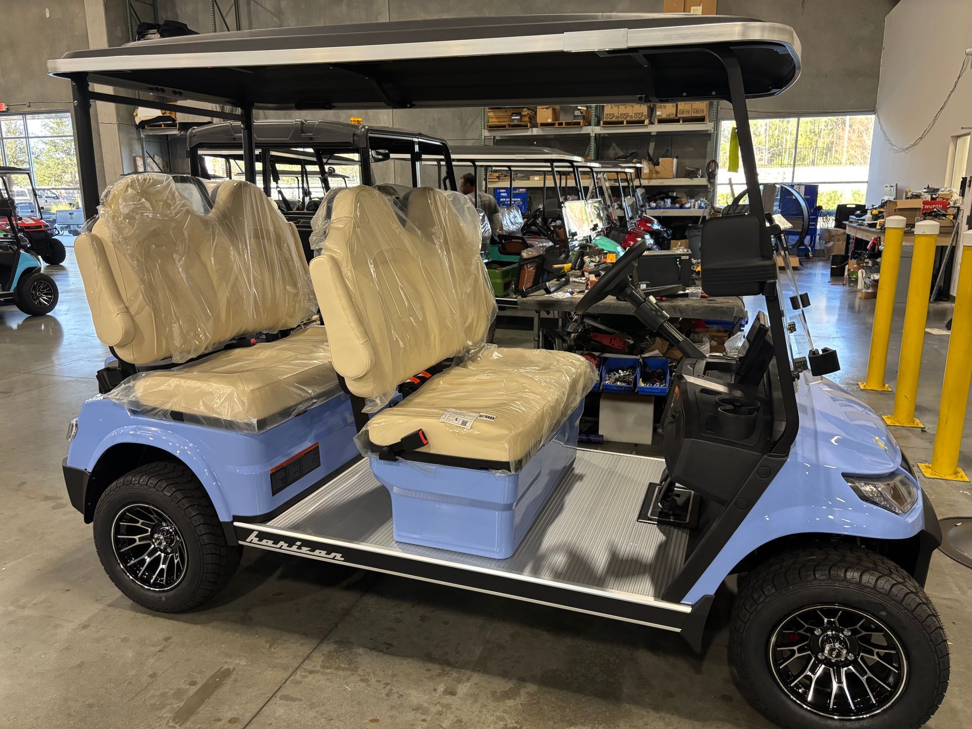 Blue golf cart with beige seats inside a warehouse.