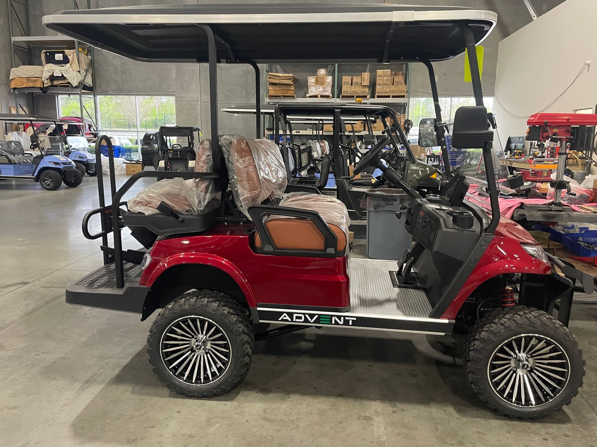 Red golf cart with black roof, chrome accents, and large wheels in an indoor setting.