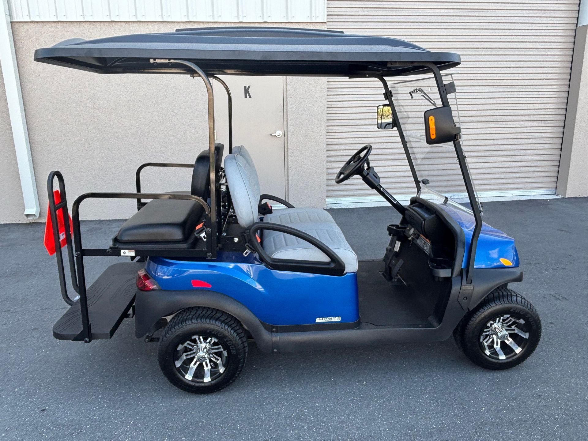 Blue golf cart with black roof parked near a building.