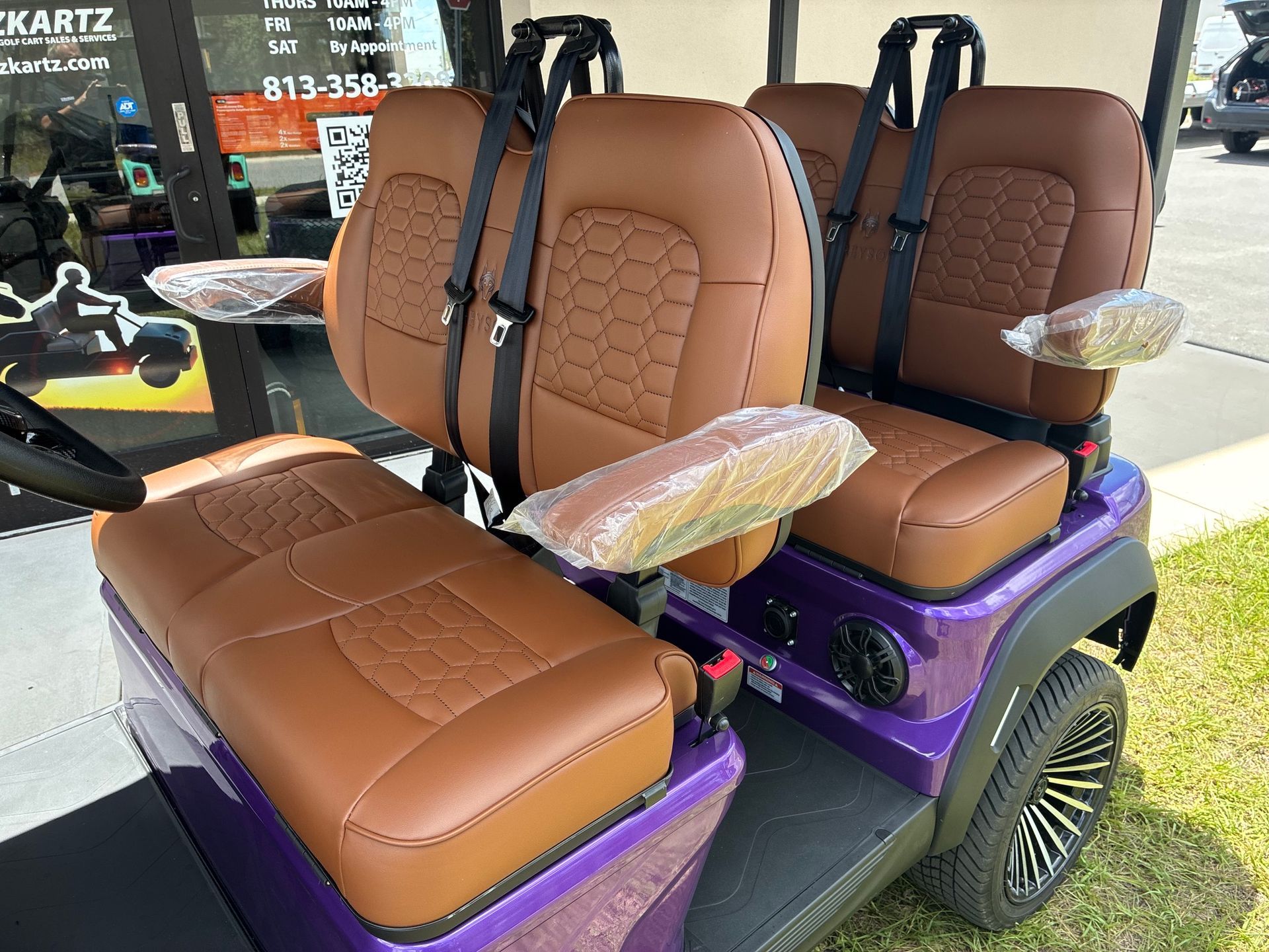 Green golf cart with black roof and wheels, parked in front of a banner.