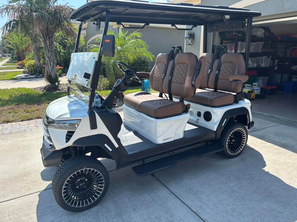 Black golf cart with red seats, parked in a shop.