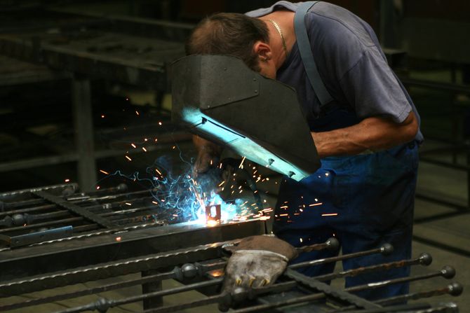 man welding a wrought iron fence