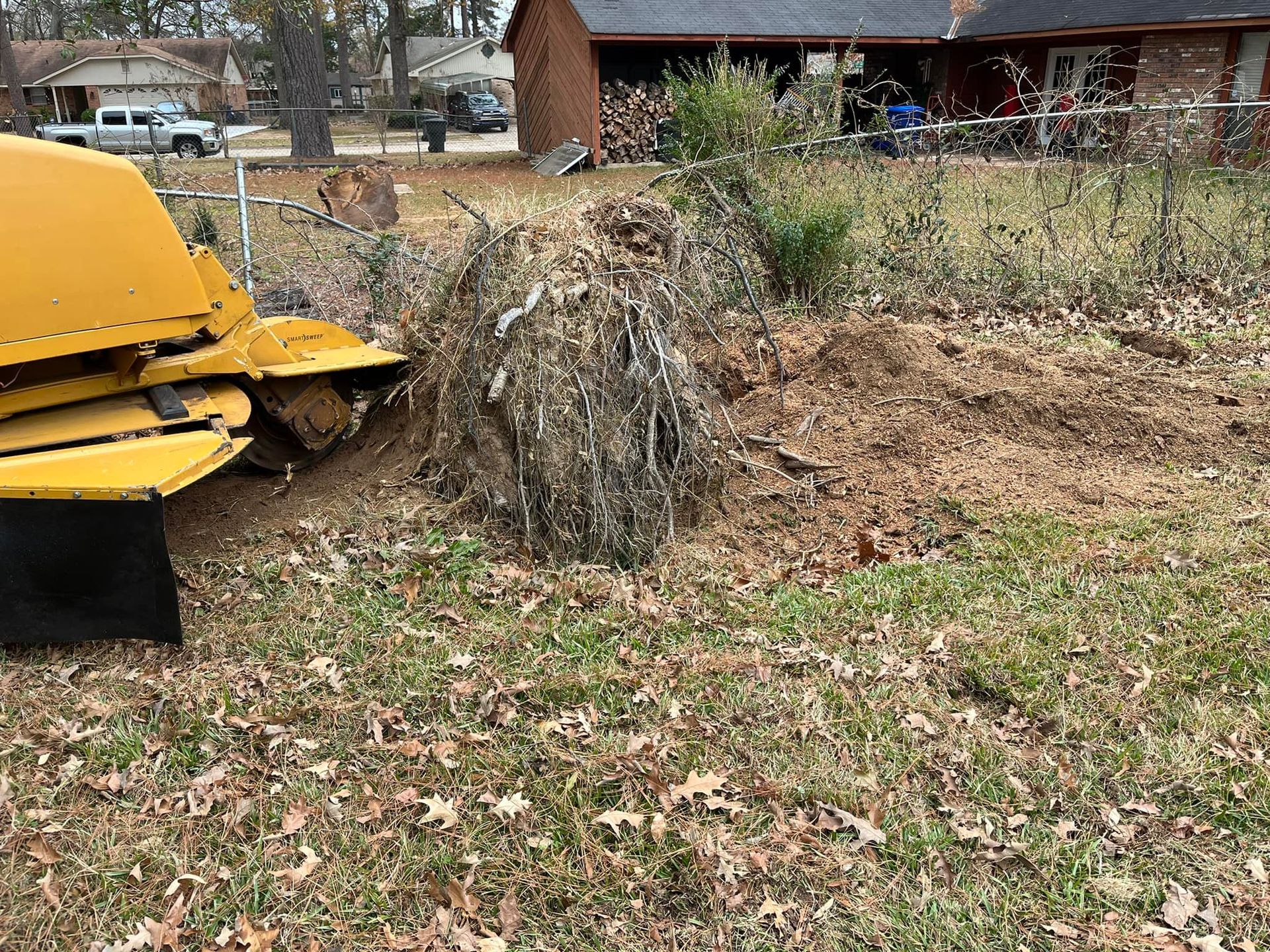 Yellow mower next to a large brush pile in a yard with fallen leaves