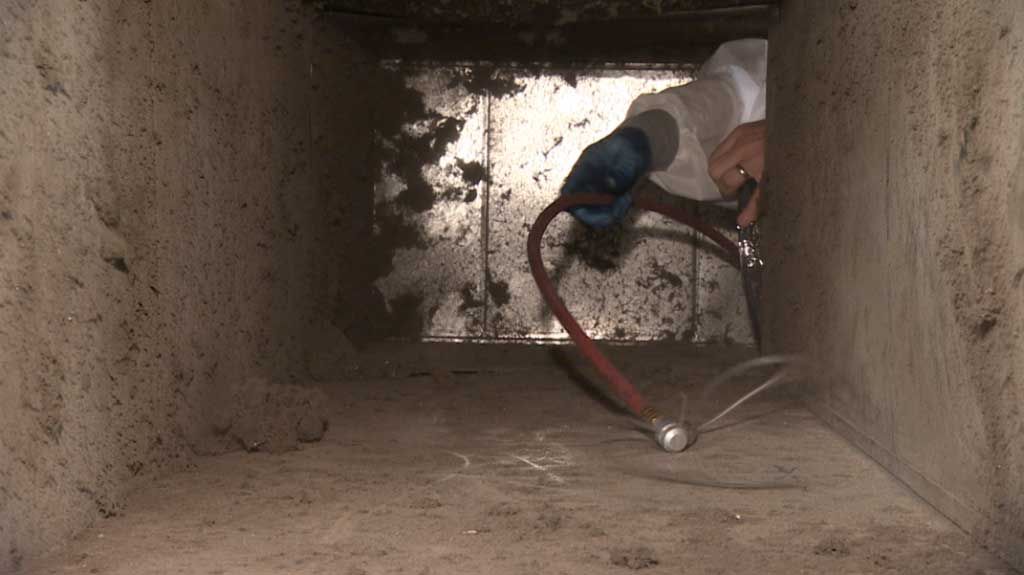 A person is cleaning a duct with a hose.
