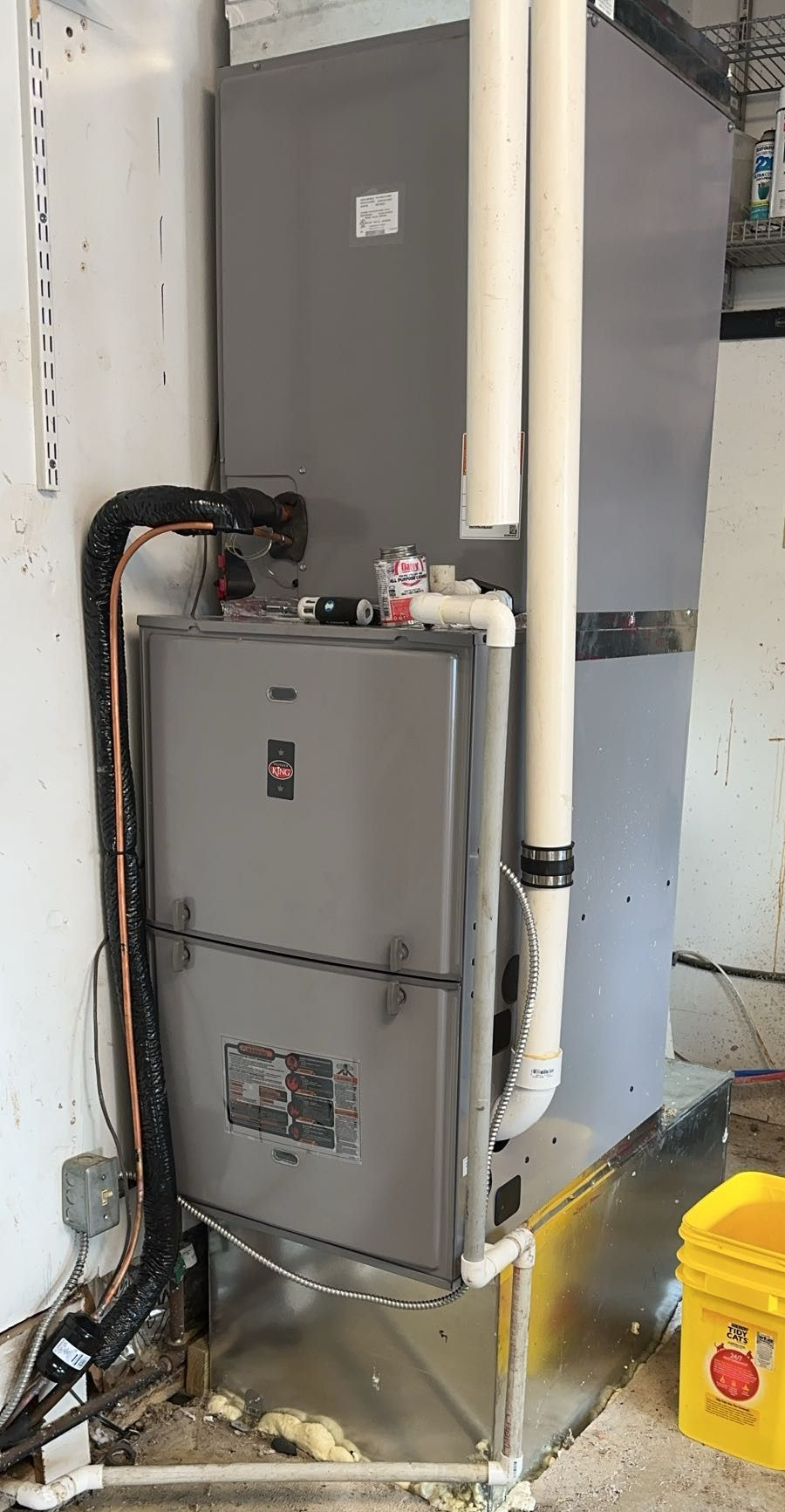 Furnace and utility area with shelving, cardboard box, and supplies.