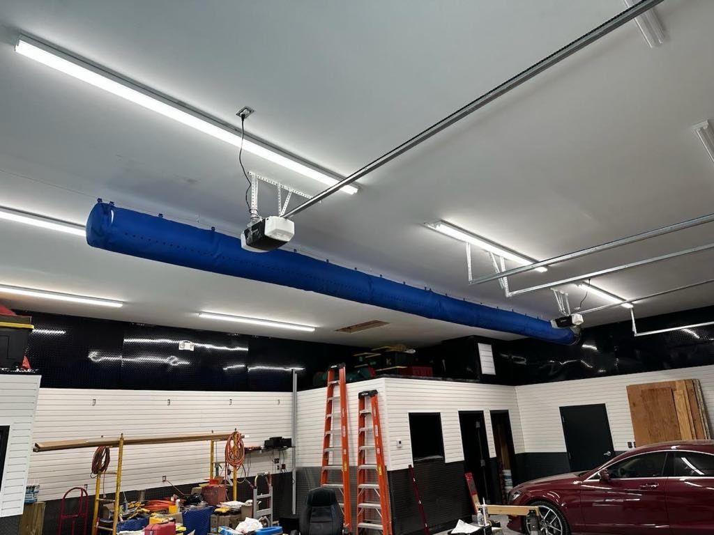 A car is parked in a garage with a blue pipe hanging from the ceiling.