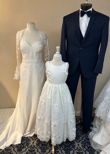 A bride and groom are standing next to a flower girl in a wedding dress.