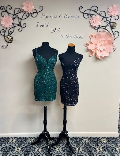 Two mannequins are standing next to each other in front of a wall.
