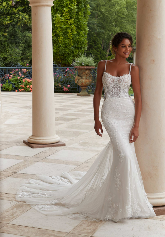 A woman in a wedding dress is leaning against a pillar - Salina, KS - Princess & Penguin Formalwear