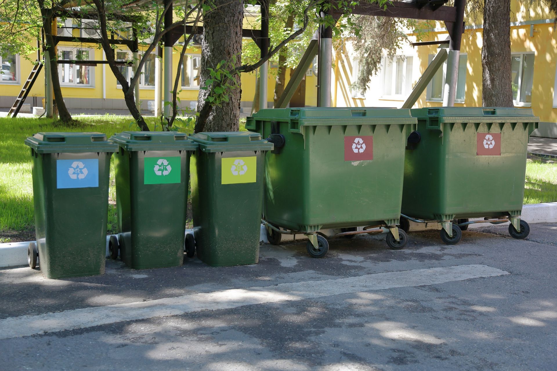 A row of green garbage cans with recycling labels on them