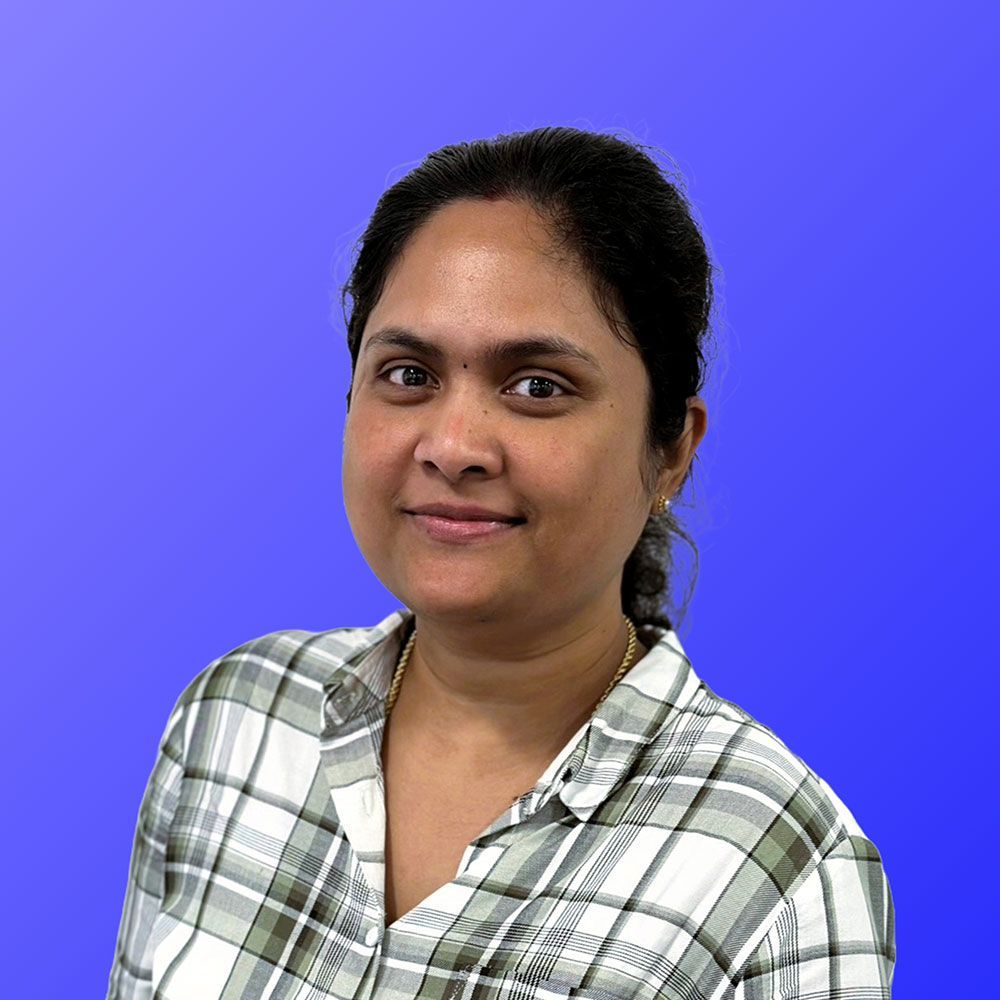 A woman in a plaid shirt is standing in front of a blue background.