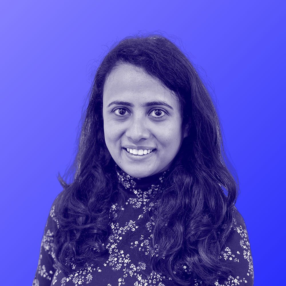 A woman is smiling in a black and white photo against a blue background.
