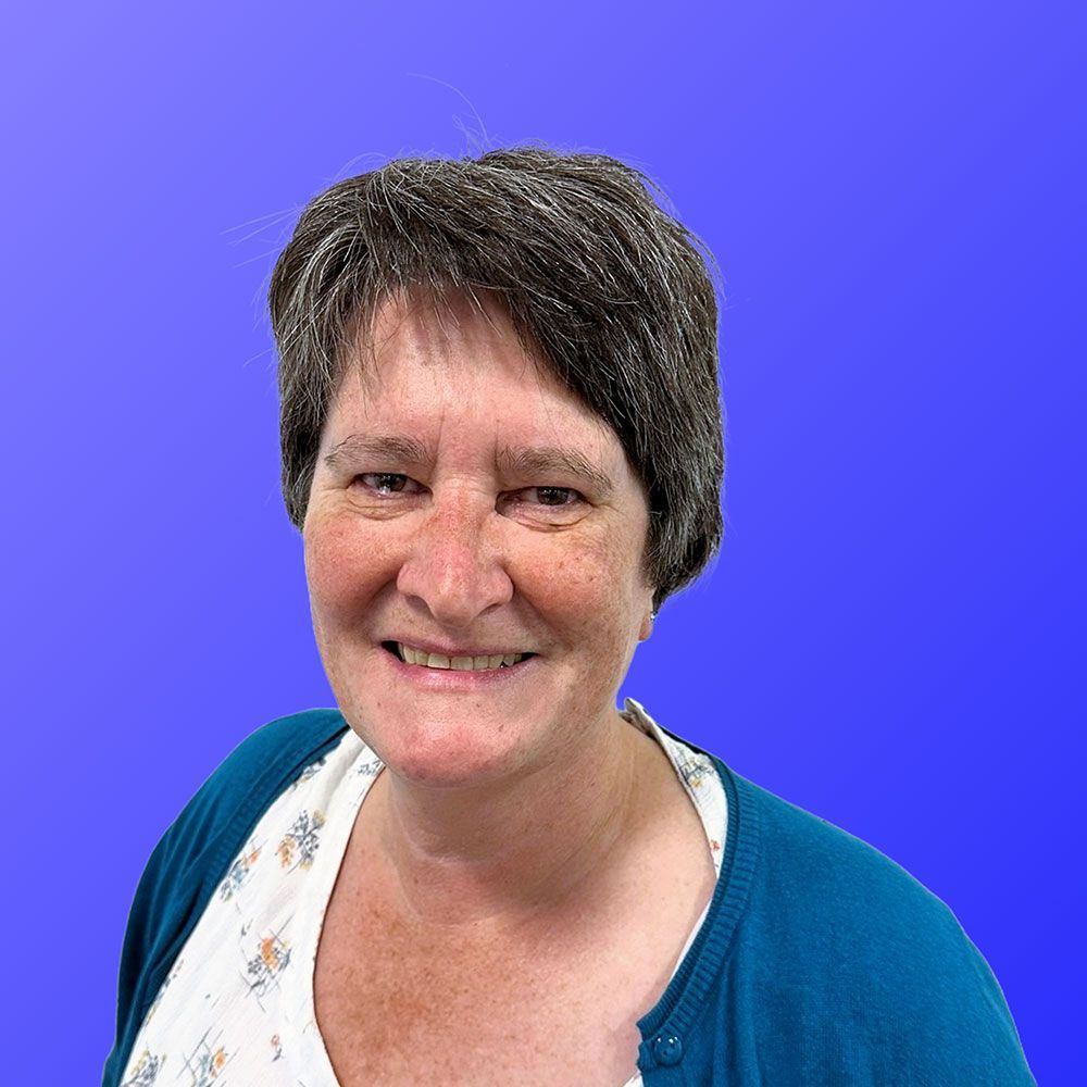 A woman in a blue sweater is smiling in front of a blue background.