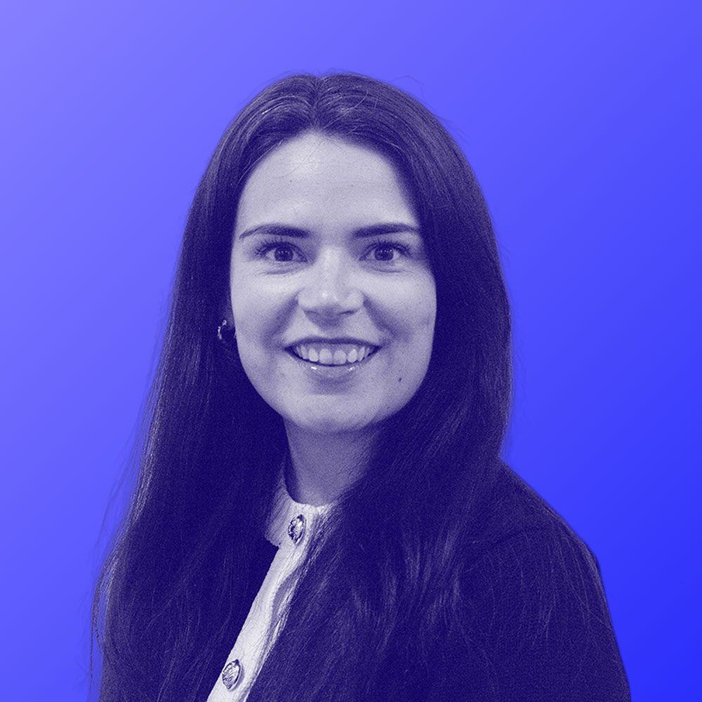 A woman is smiling in a black and white photo with a blue background.