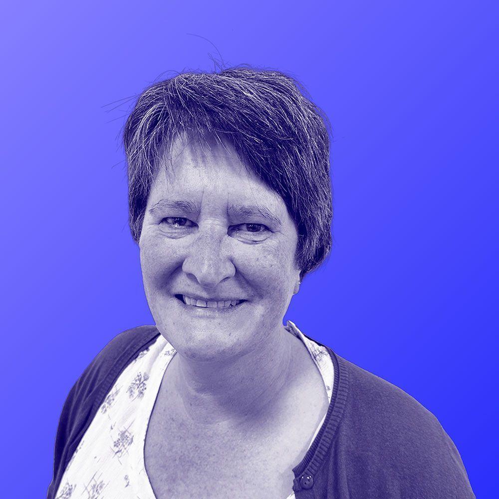 A woman is smiling in a black and white photo against a blue background.