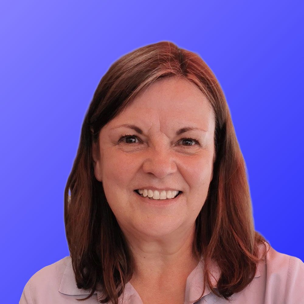 A woman with long brown hair is smiling in front of a blue background.