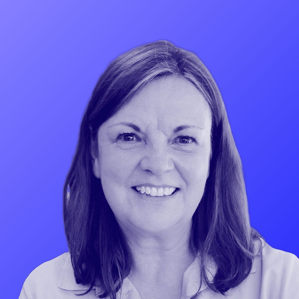 A woman is smiling in a black and white photo with a blue background.
