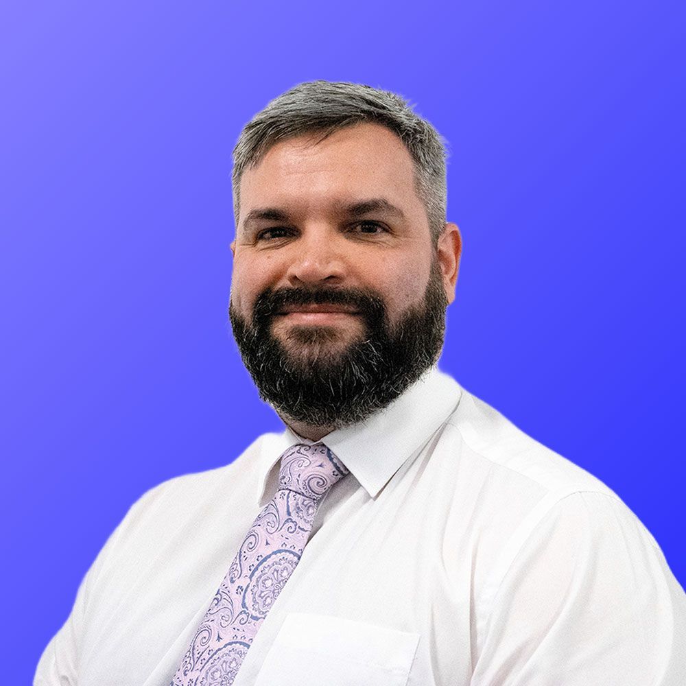 A man with a beard is wearing a white shirt and tie.