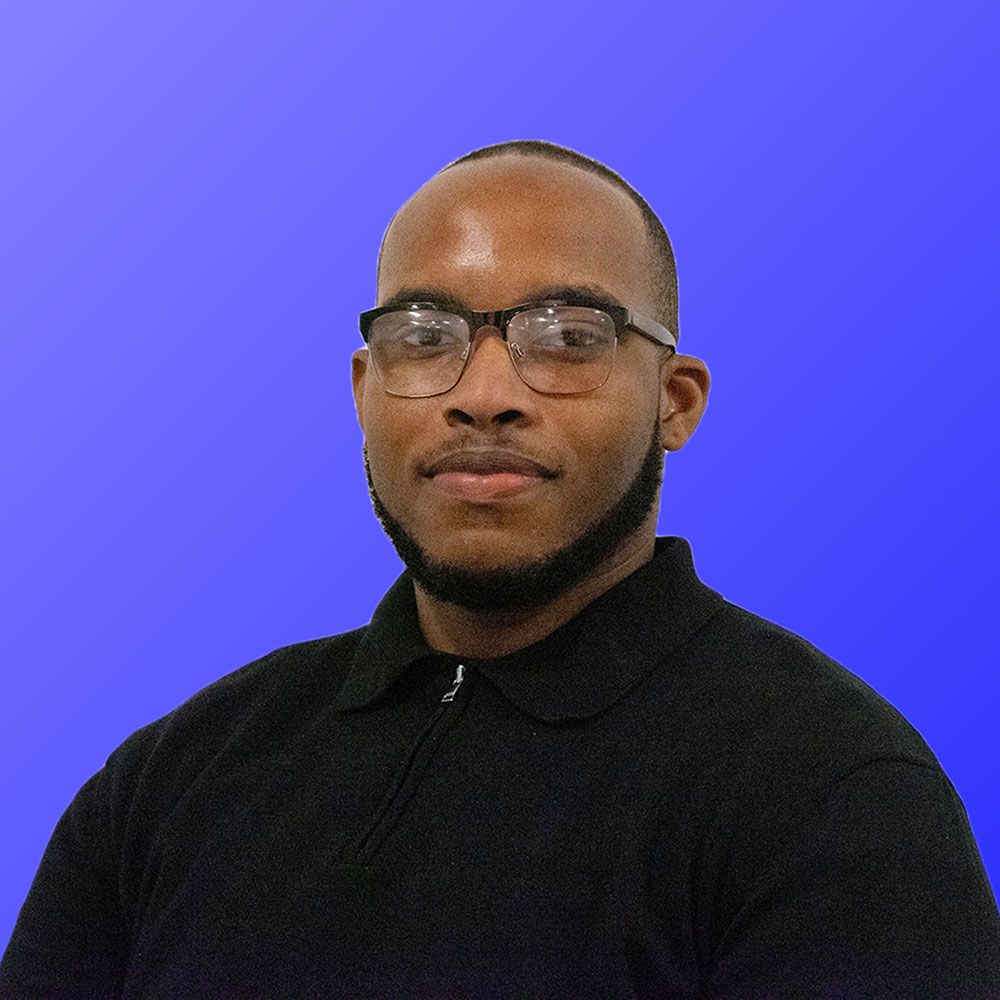 A man wearing glasses and a black shirt is standing in front of a blue background.