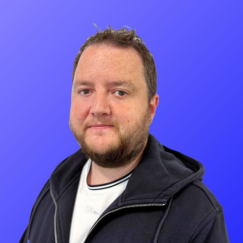 A man with a beard is wearing a black hoodie and a white shirt.