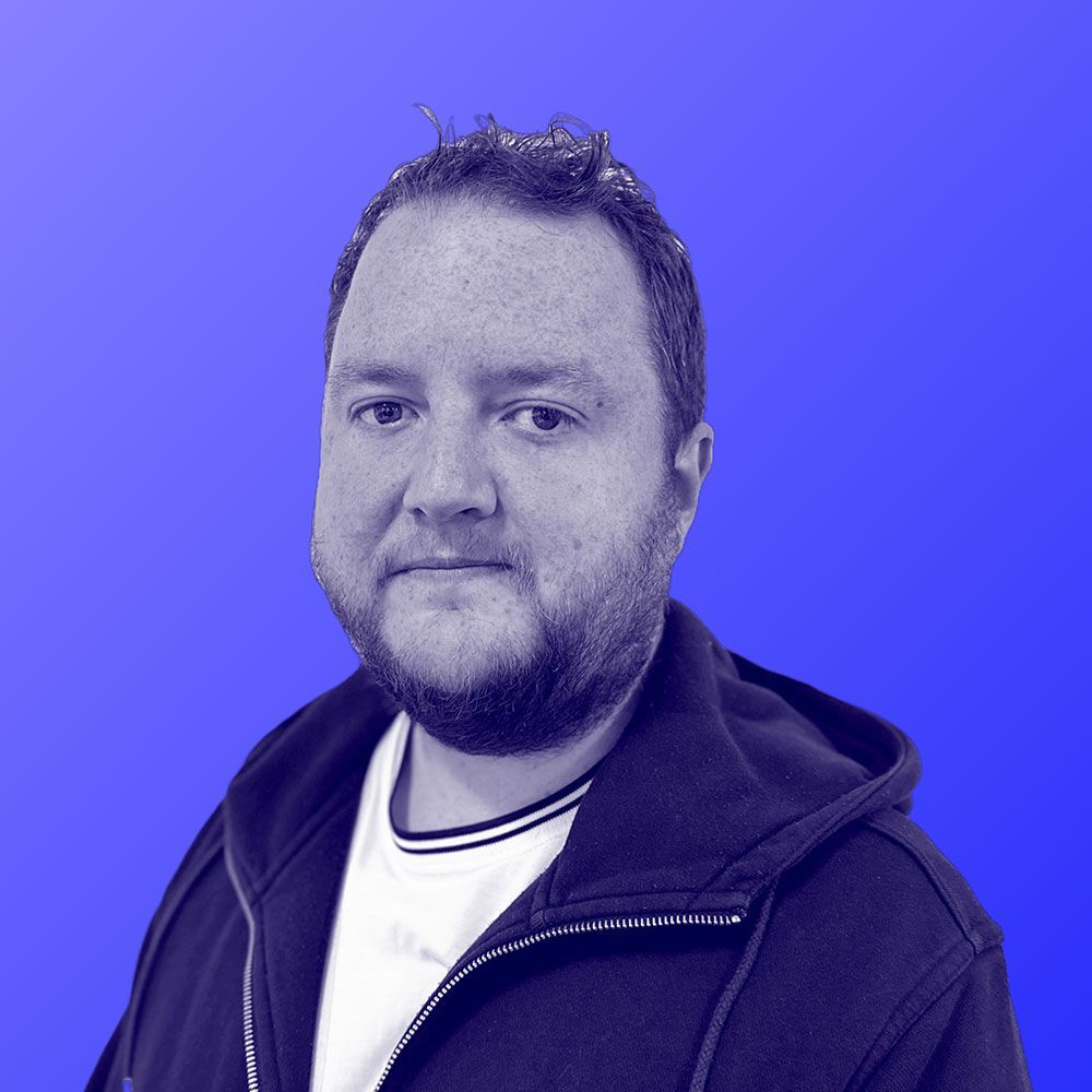 A man with a beard is wearing a black hoodie and a white shirt.