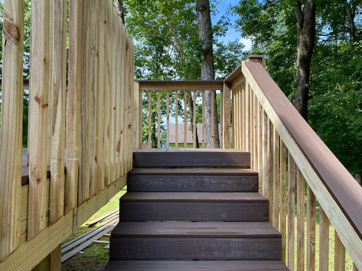 Wooden stairs with railings leading up through a wooded outdoor area