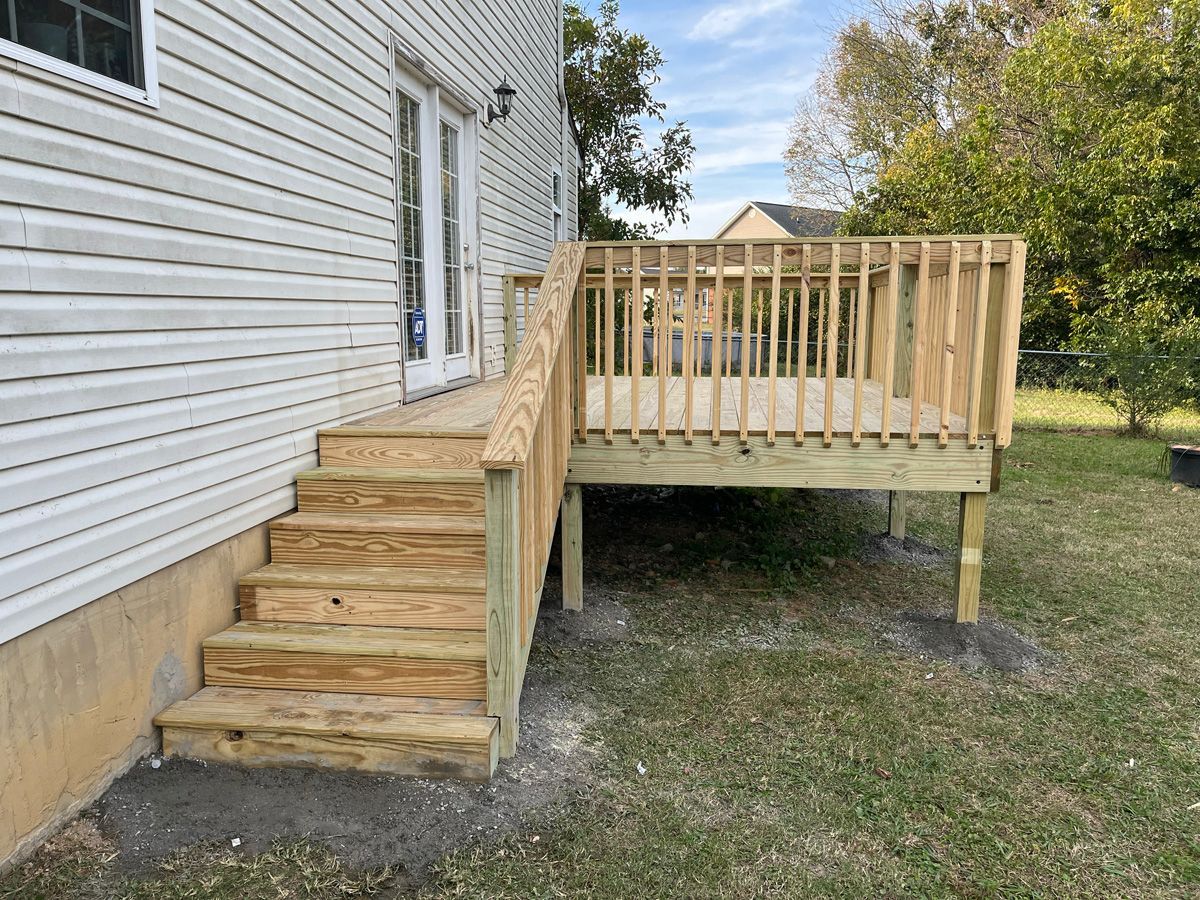 Wooden accessibility ramp and steps attached to a white house with a small porch.
