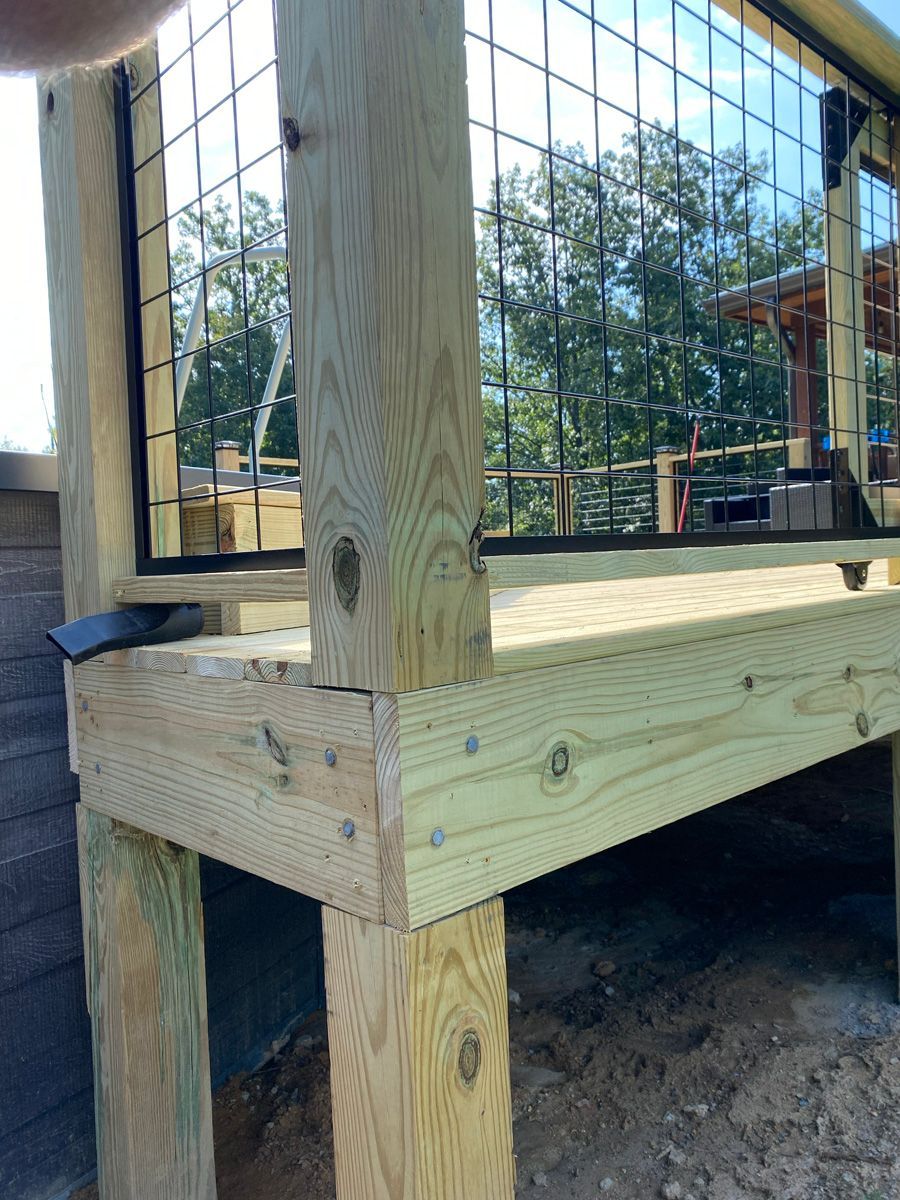 Wooden deck corner with posts and railing, showing a close-up of unfinished lumber outdoors.