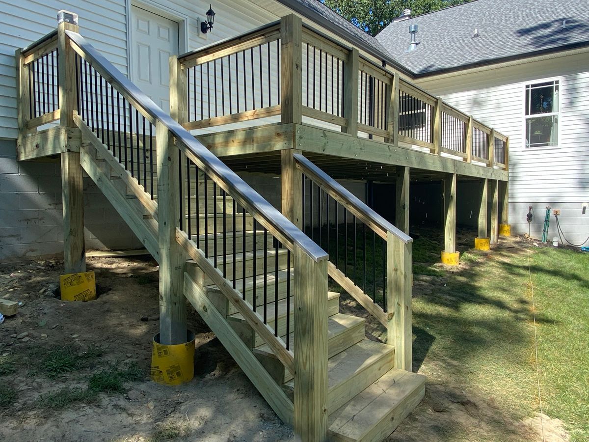 Wooden backyard deck with stairs and railings attached to a white house.