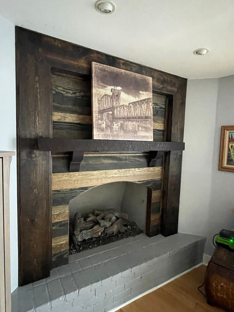 Built-in dark wood fireplace mantel with stone firebox and framed art above, in a light gray room