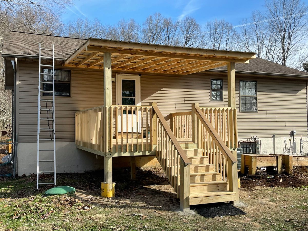 Small wooden porch with stairs and ramp attached to a beige house, with a ladder on the left side.