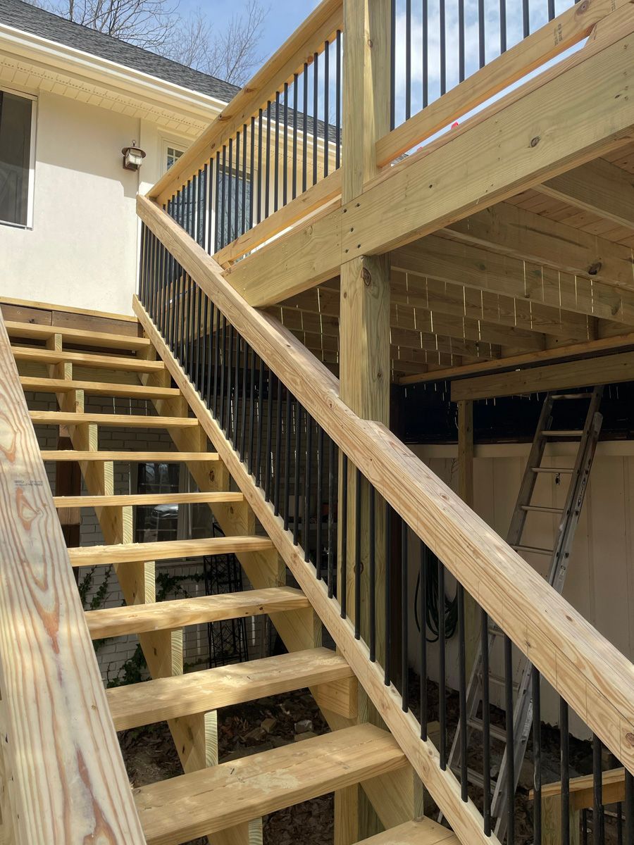 Wooden outdoor staircase and balcony under construction beside a house