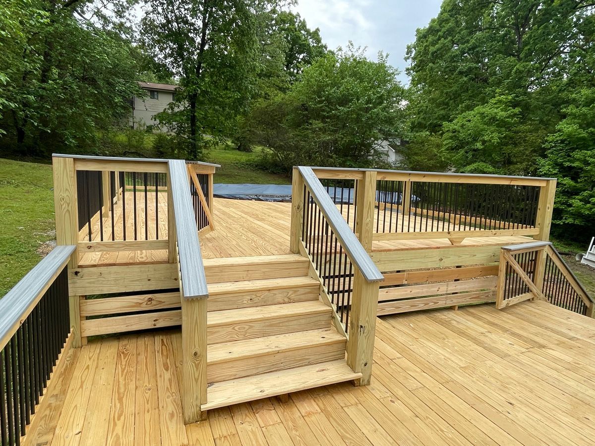 Wooden wheelchair-accessible deck with central steps and side ramps in a wooded outdoor setting