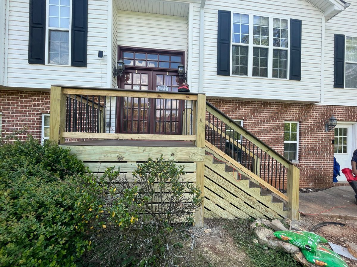 Front porch with wooden ramp and steps leading to a white-and-brick house entrance
