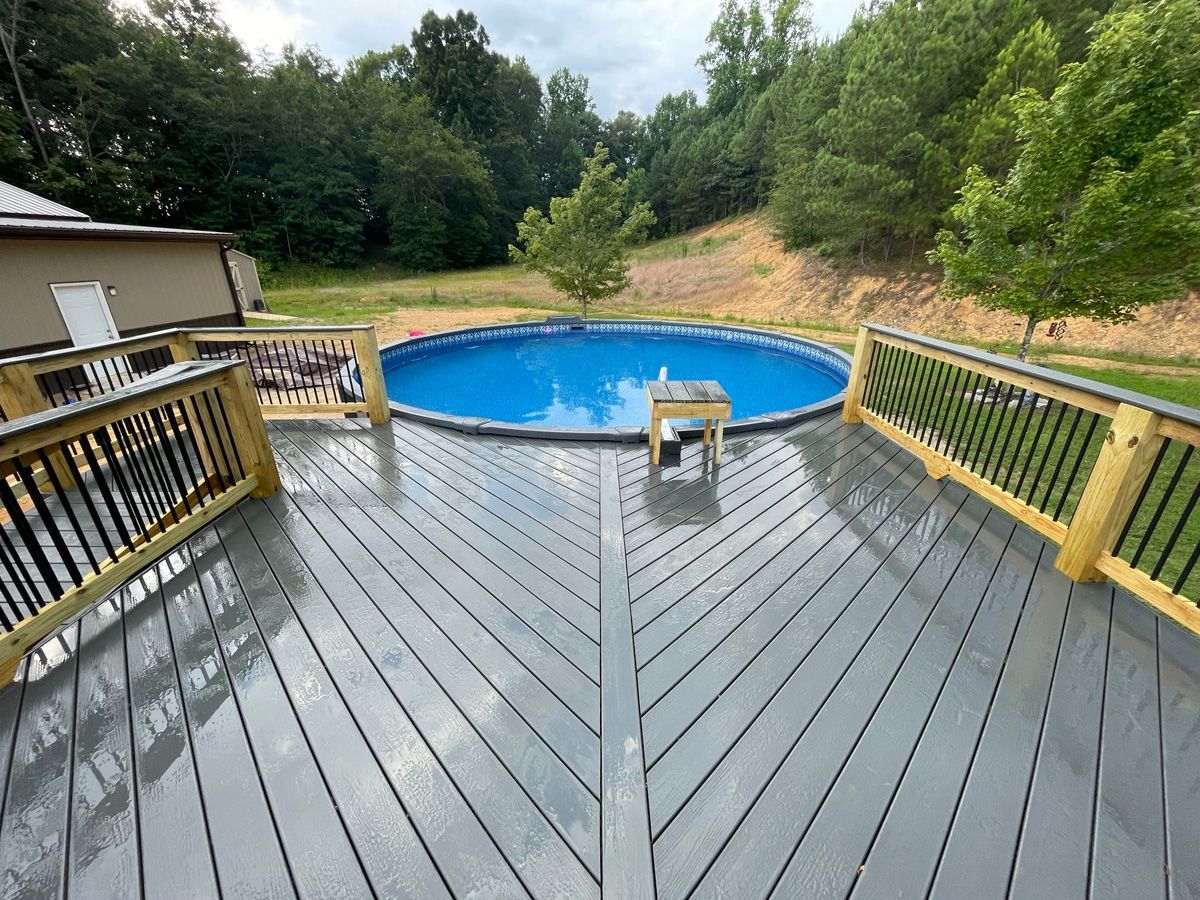 Back deck overlooking a blue swimming pool, surrounded by trees and grassy hillside