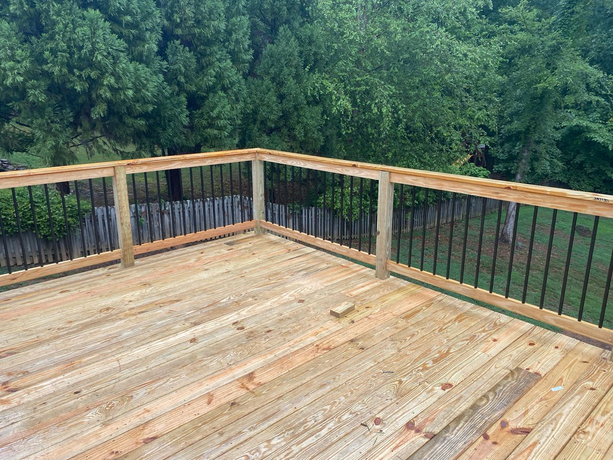 Wooden deck with railing overlooking dense green trees and a forested view