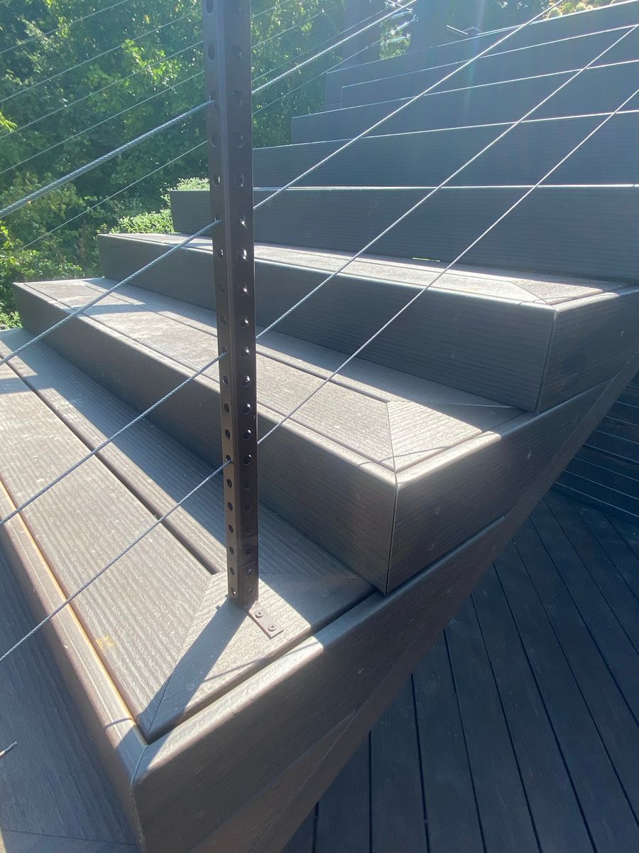 Outdoor stepped seating with metal railing in bright sunlight on a wooden deck