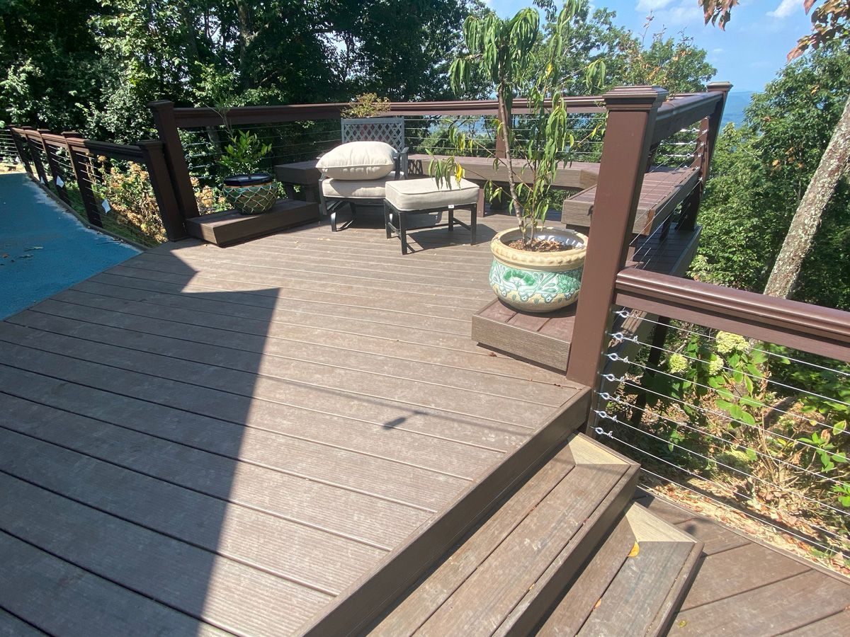 Wooden backyard deck with lounge chair, small table, and potted plants beside a garden path