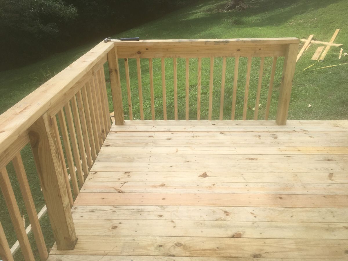 Wooden deck with railing overlooking a grassy yard and trees