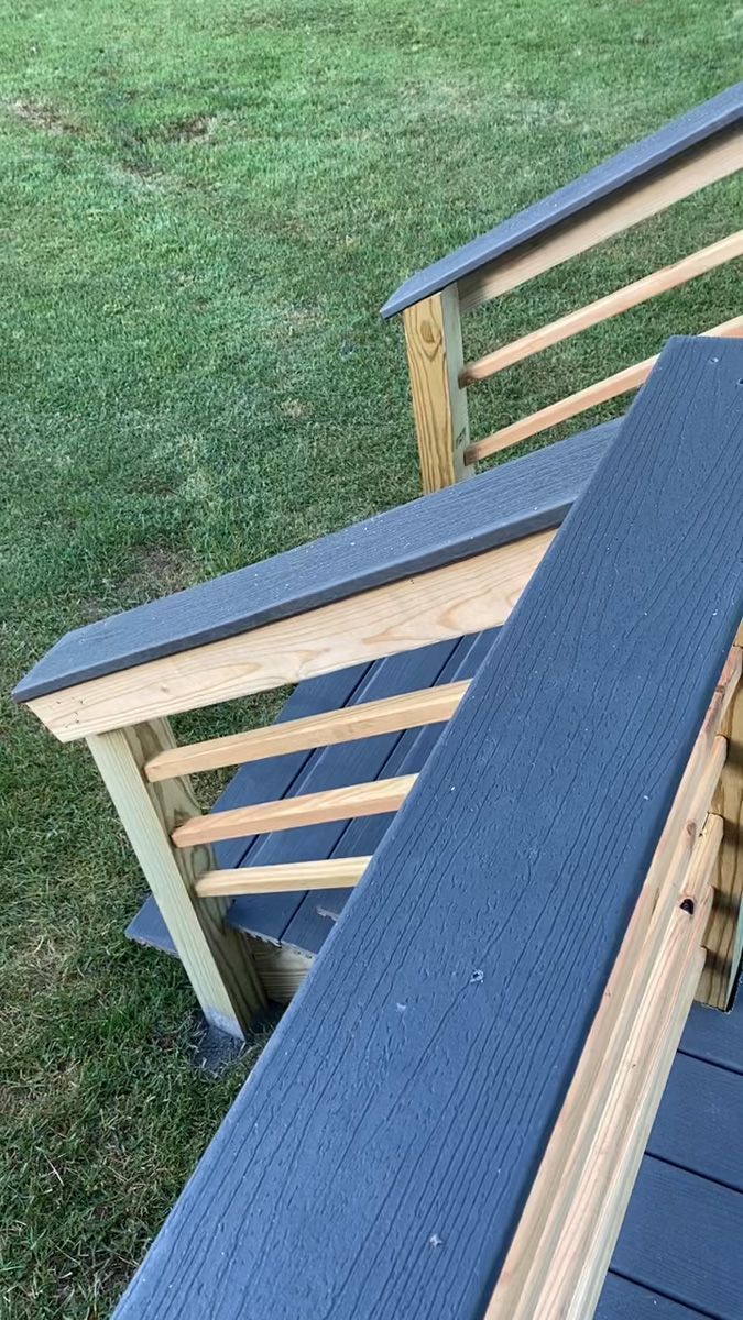 Two blue-cushioned wooden outdoor chairs on a deck beside a grassy yard