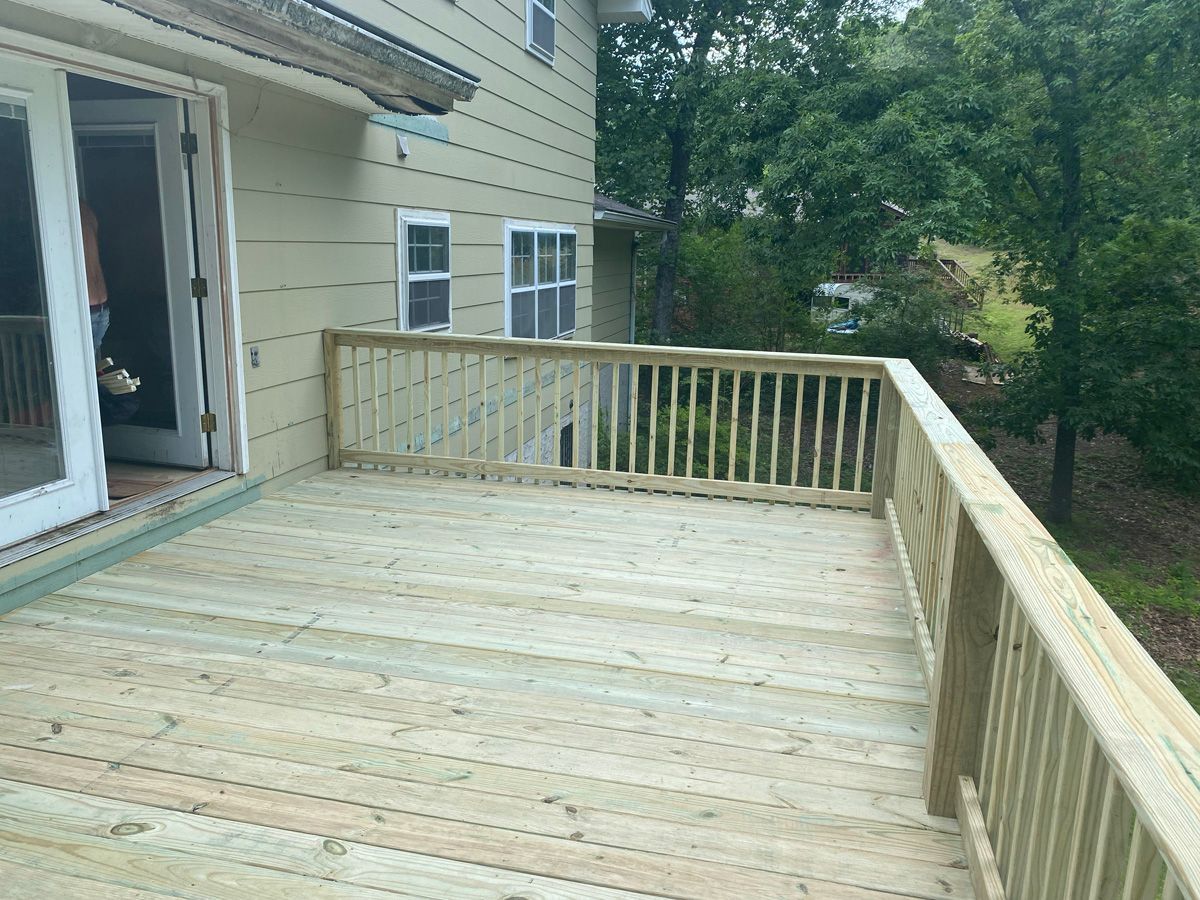 Wooden backyard deck beside a house, with railings and a view of trees and lawn