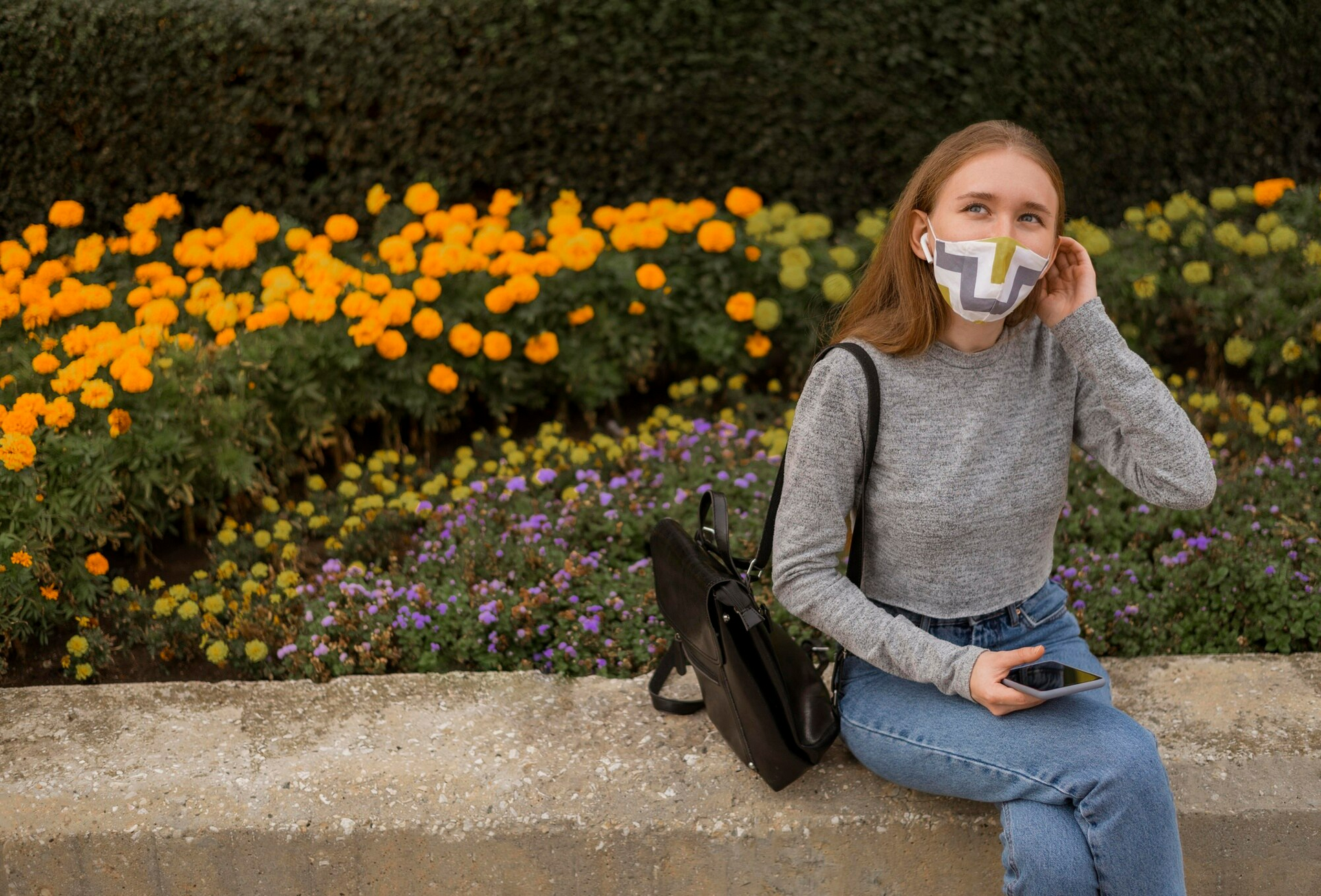 A woman wearing a face mask shields herself from pollen allergy while enjoying time outdoors. 
