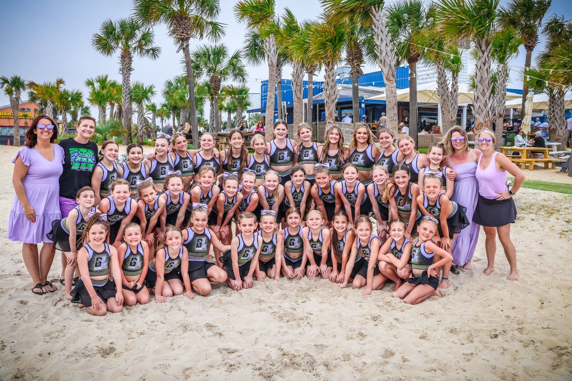 A group of young girls are posing for a picture on the beach.
