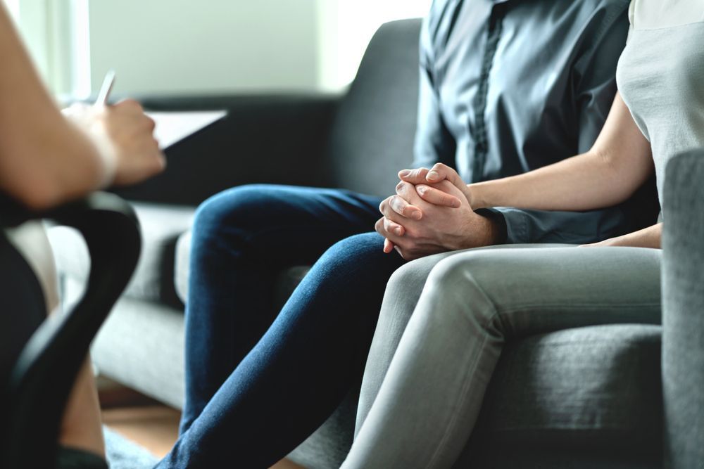 Couple Holding Hands, Sitting on a Couch in Therapy Session — AT My Place Counselling and Psychotherapy in Neutral Bay, NSW
